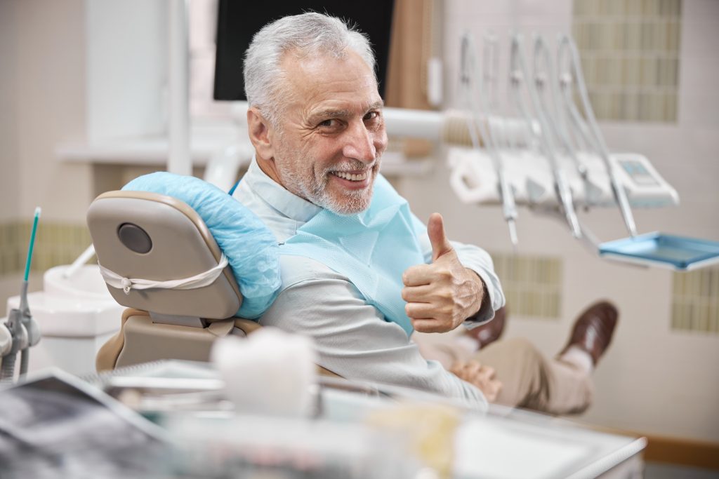 older man smiling in a dentist chair