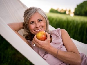 woman smiling while holding an apple
